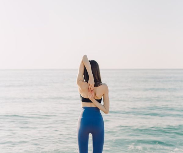 Person stretching gently outdoors during a calm morning.